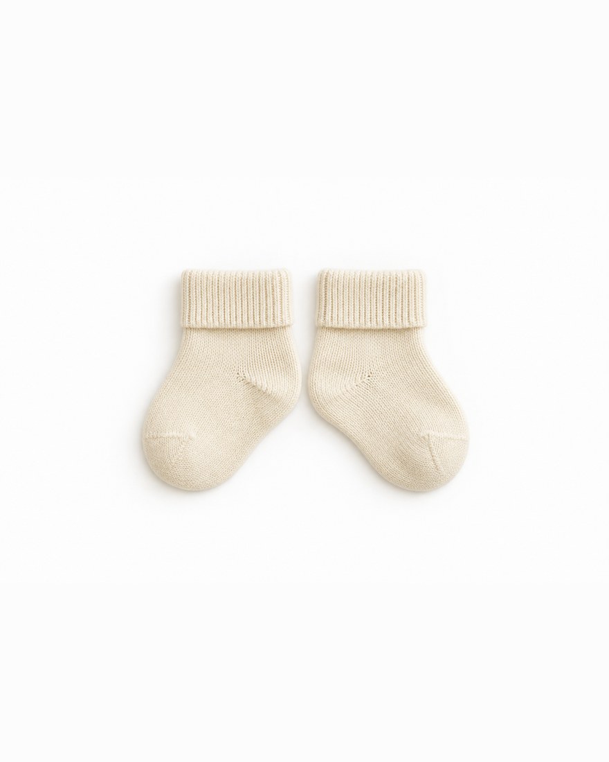 Pair of ivory knitted bamboo newborn socks laid flat